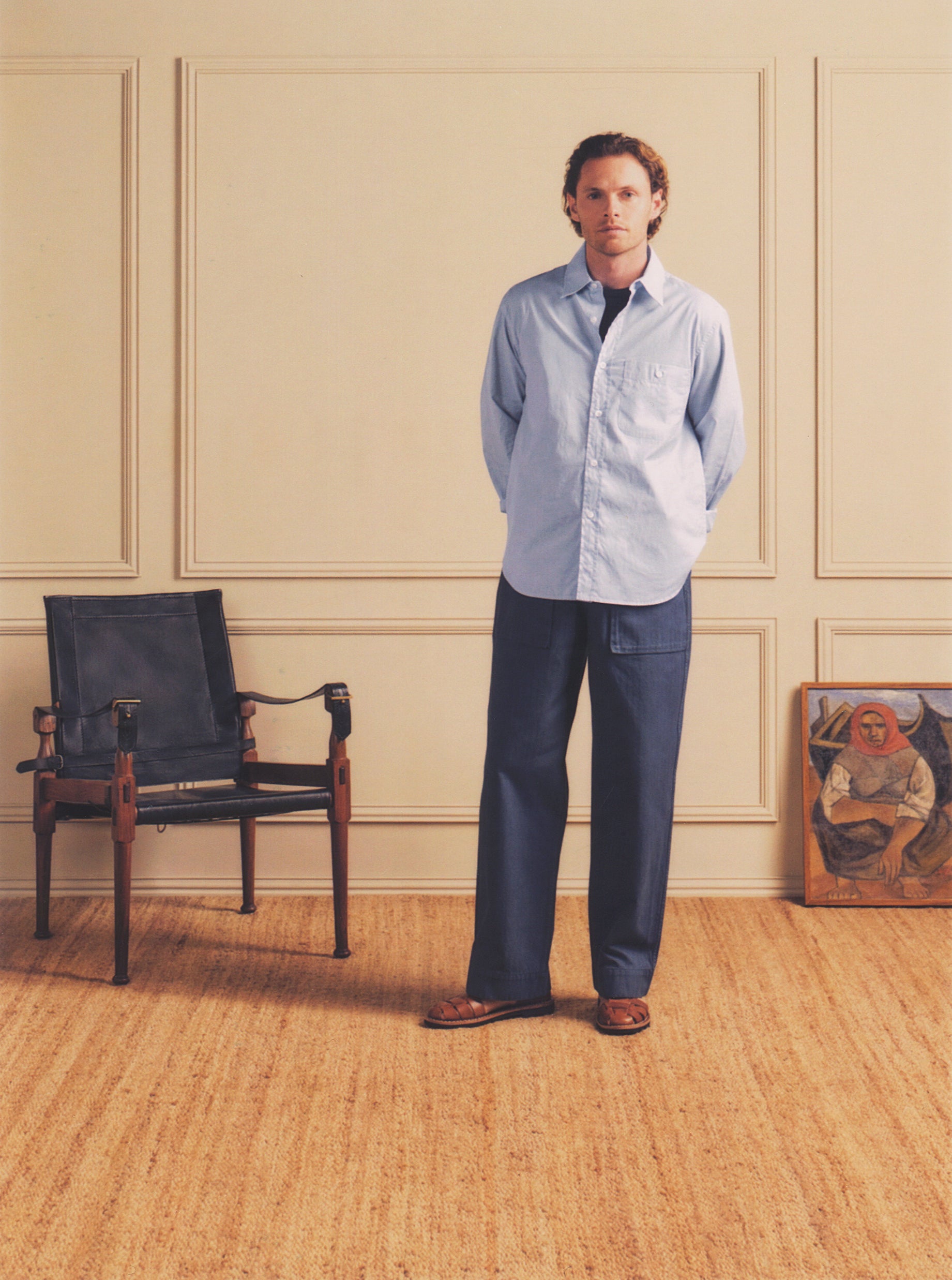Man standing in a room with a chair and painting in the background